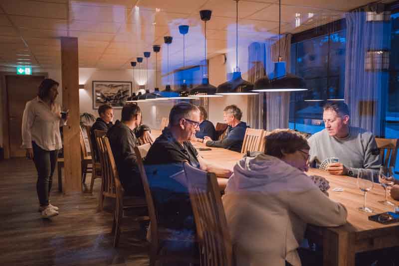 Geselliges Beisammensein im Wohnzimmer von Tgiesa Solaria – Kartenabend unter Freunden Eine Gruppe geniesst einen Kartenabend im gemütlichen Wohnzimmer von Tgiesa Solaria